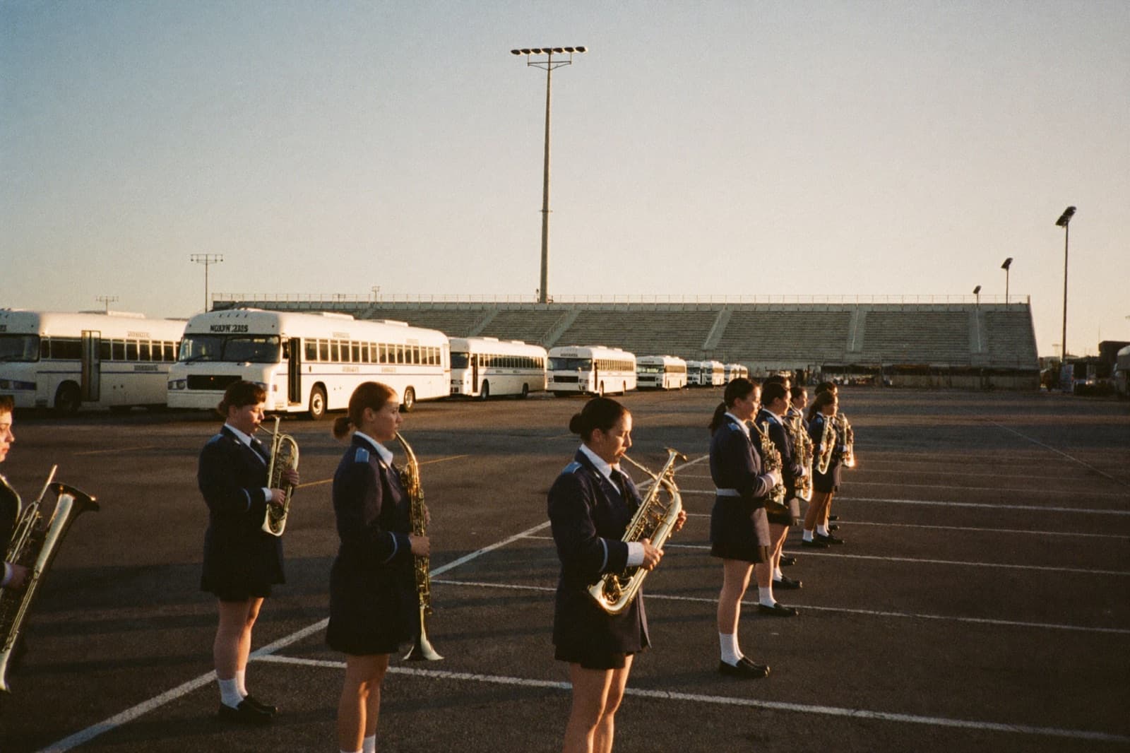 A marching band boards its buses at dawn before a trip.